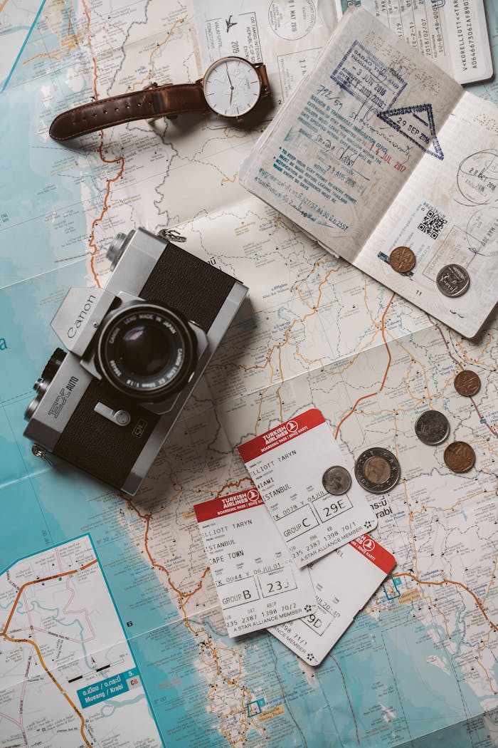 why-choose-us Flat lay travel essentials including passports, tickets, and a vintage camera on a world map.